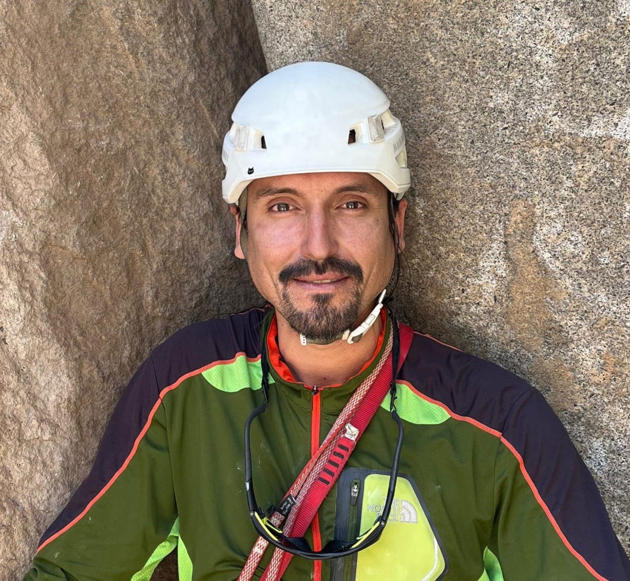 Pablo Castillo wearing a white climbing helmet beside a rock wall.