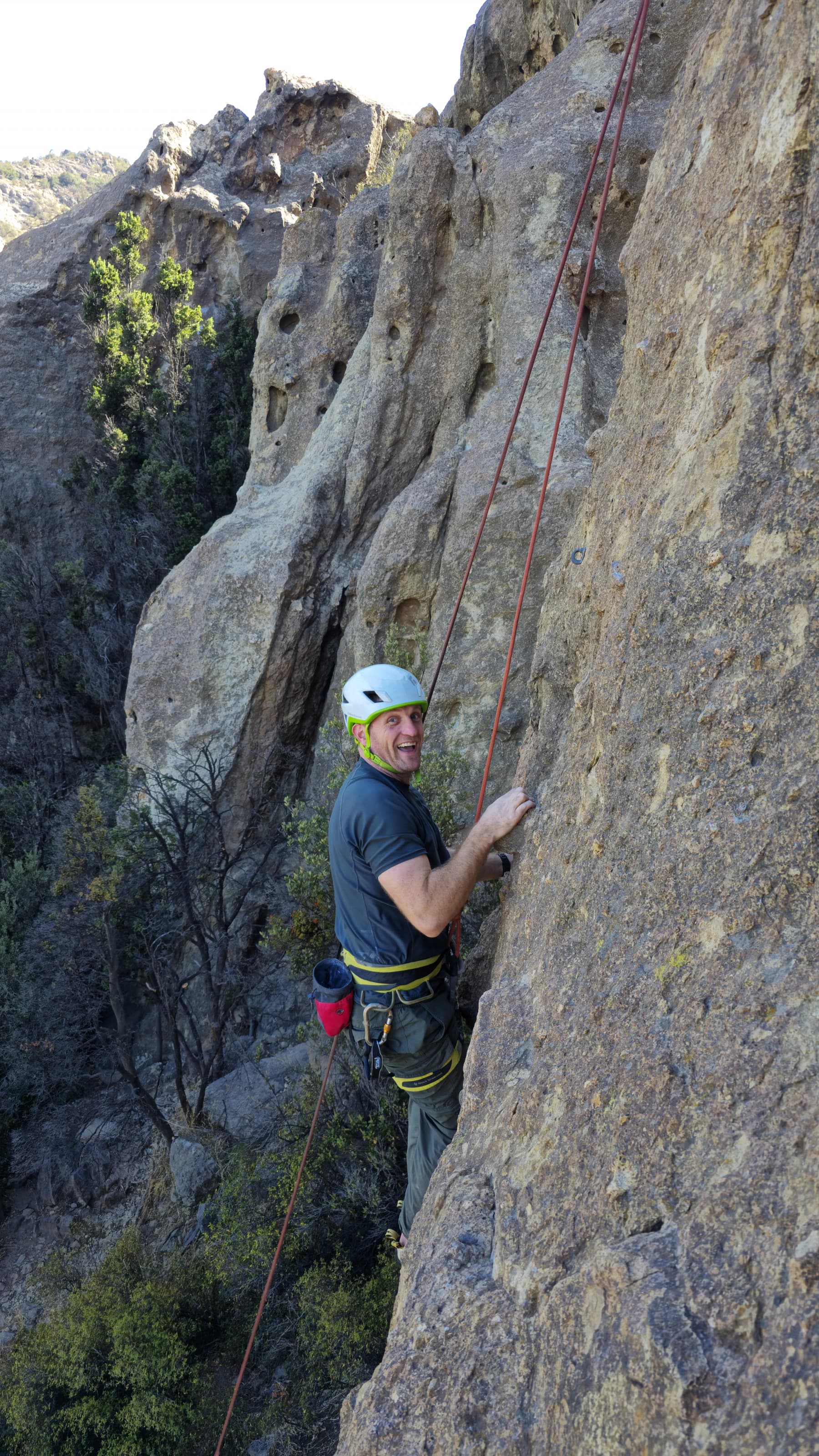 A climber smiling on a roped rock route during a private guiding day.